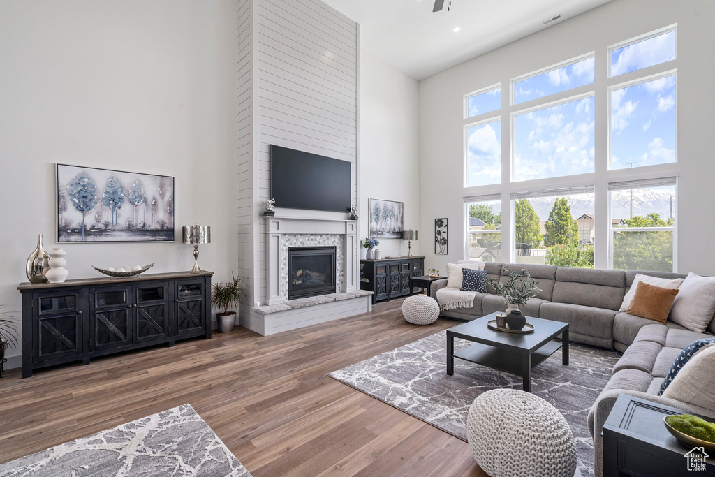 Living room featuring a towering ceiling, a fireplace, and wood-type flooring