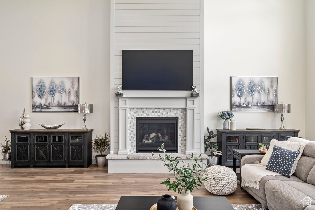 Living room featuring wood-type flooring, a towering ceiling, and a tile fireplace