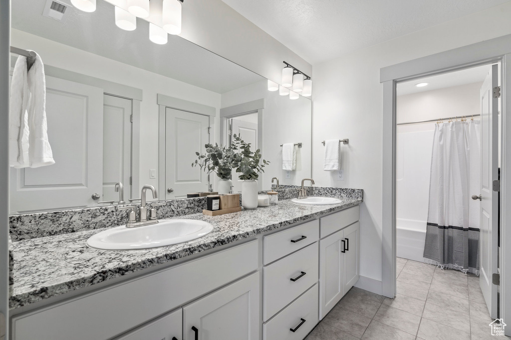 Bathroom with tile flooring, oversized vanity, dual sinks, and shower / tub combo