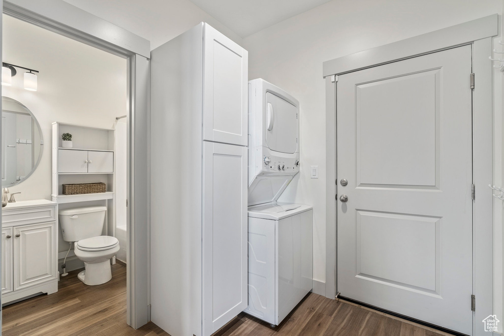 Washroom featuring stacked washer and clothes dryer and hardwood / wood-style flooring