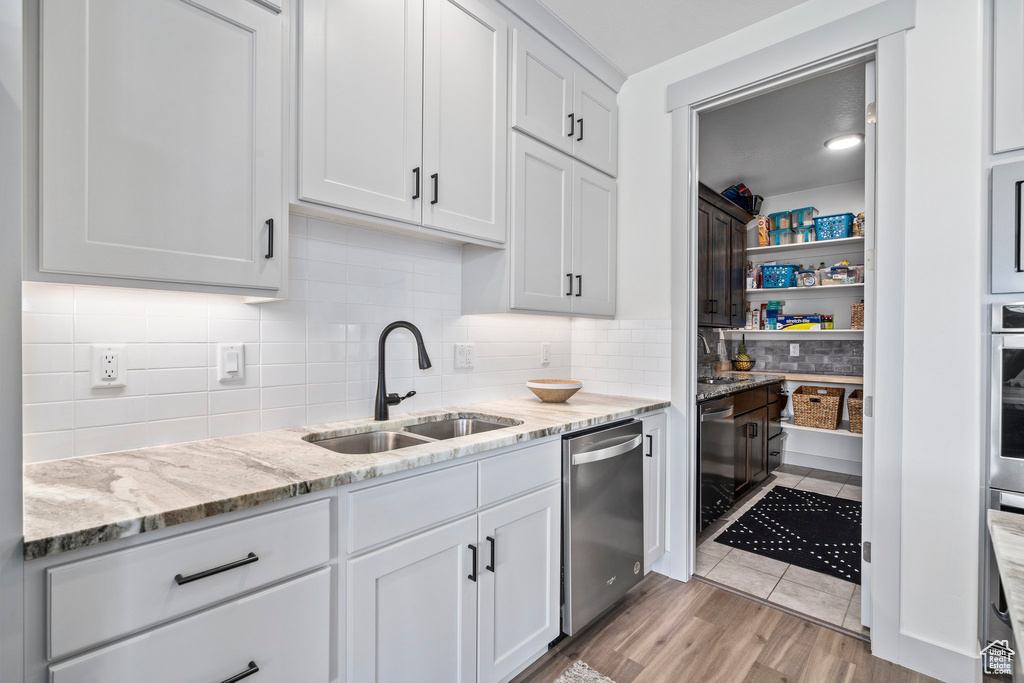 Kitchen featuring sink, stainless steel appliances, backsplash, and light tile floors