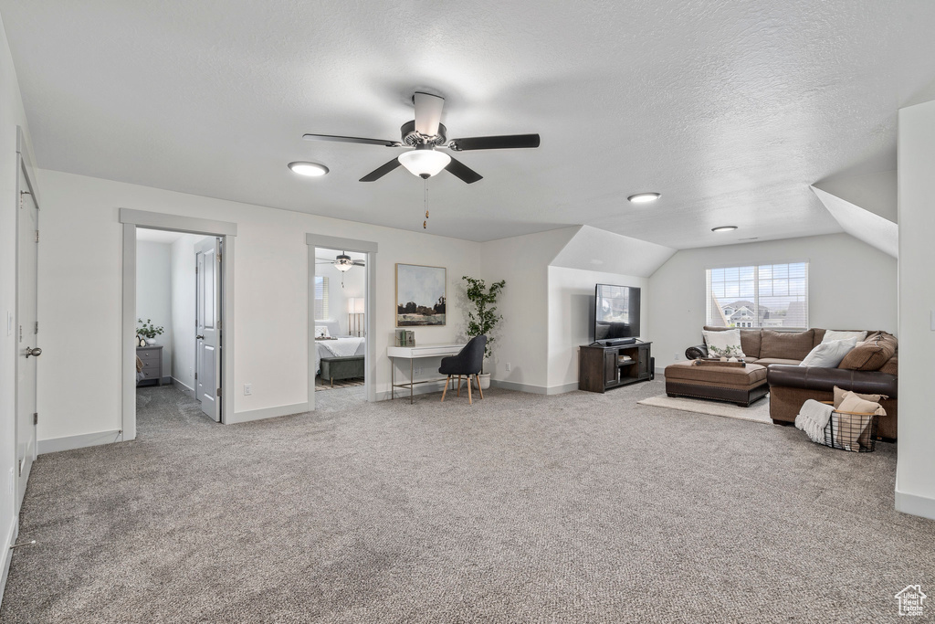 Living room with a textured ceiling, carpet, ceiling fan, and vaulted ceiling