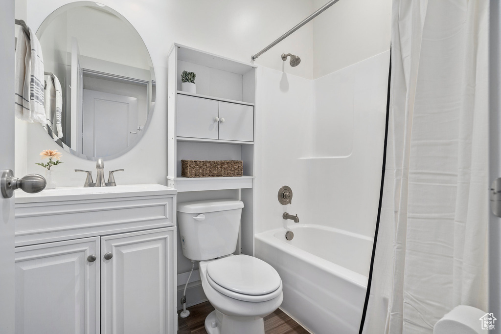 Full bathroom featuring shower / tub combo with curtain, vanity, toilet, and hardwood / wood-style floors