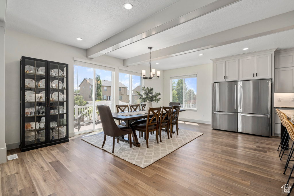 Dining space featuring beam ceiling, a notable chandelier, and hardwood / wood-style flooring