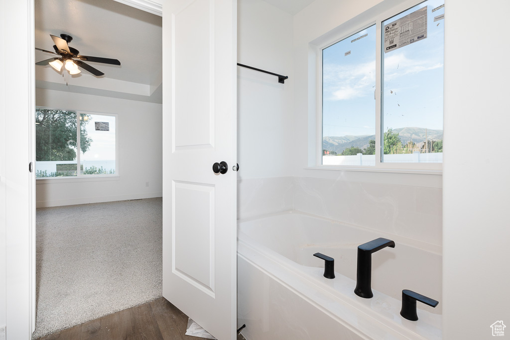 Bathroom with a bath, hardwood / wood-style flooring, and ceiling fan