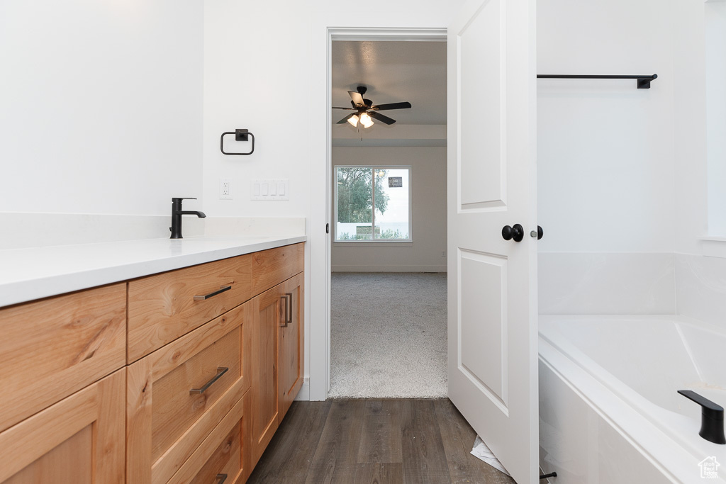 Bathroom with a tub, ceiling fan, vanity, and hardwood / wood-style flooring