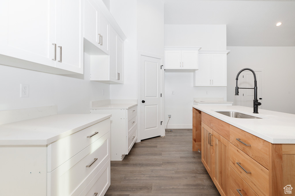 Kitchen with sink, hardwood / wood-style flooring, white cabinets, and a center island with sink