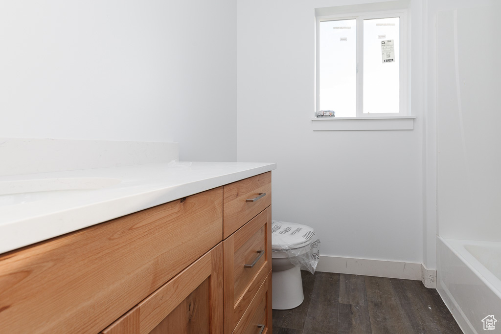 Full bathroom featuring washtub / shower combination, hardwood / wood-style floors, vanity, and toilet