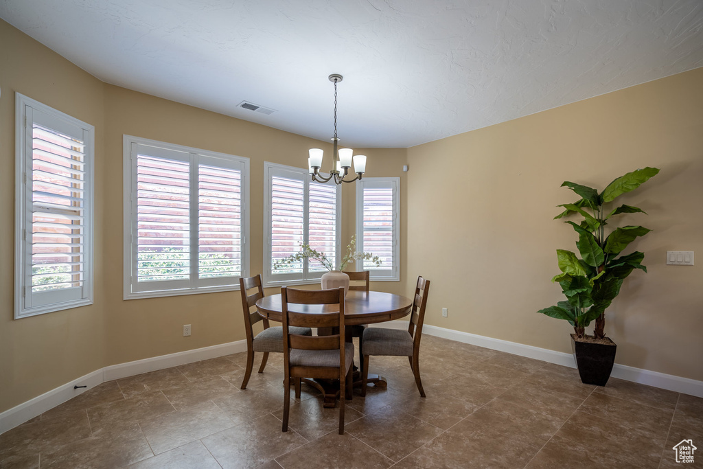 Dining room with dark tile flooring and a notable chandelier