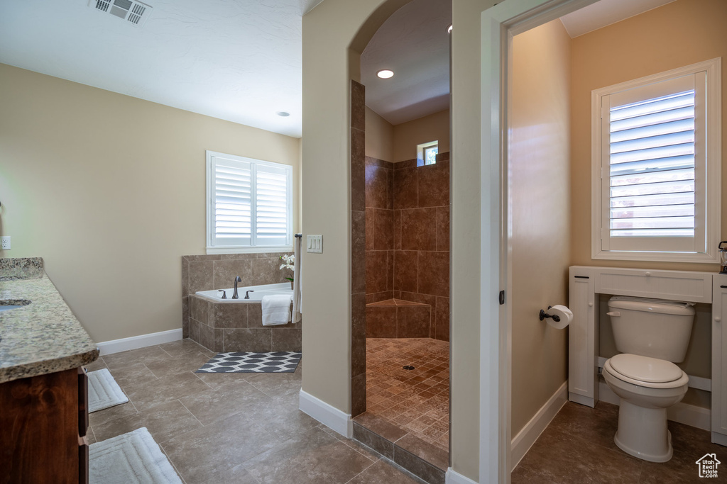 Full bathroom with tile flooring, separate shower and tub, vanity, and toilet