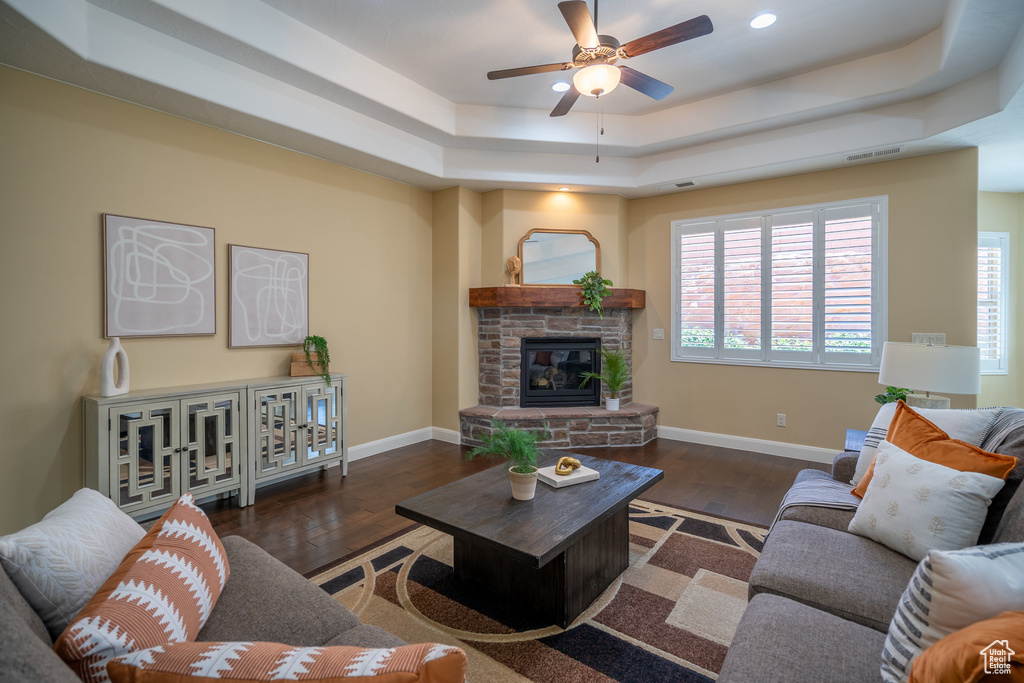 Living room with a tray ceiling, dark hardwood / wood-style floors, and a fireplace