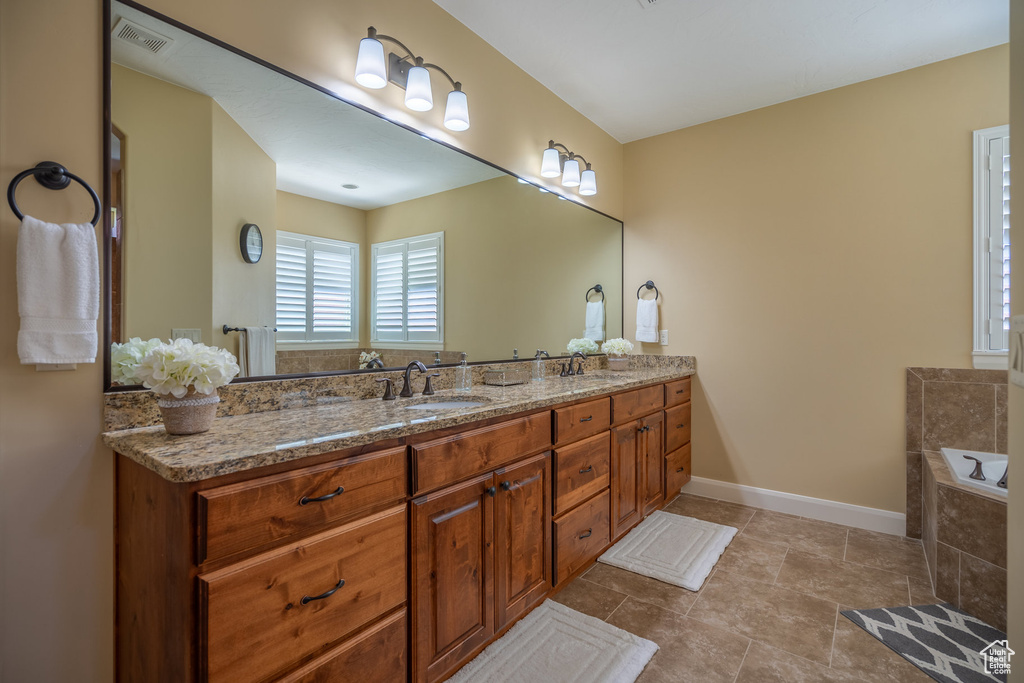 Bathroom with tile floors, dual vanity, and tiled tub