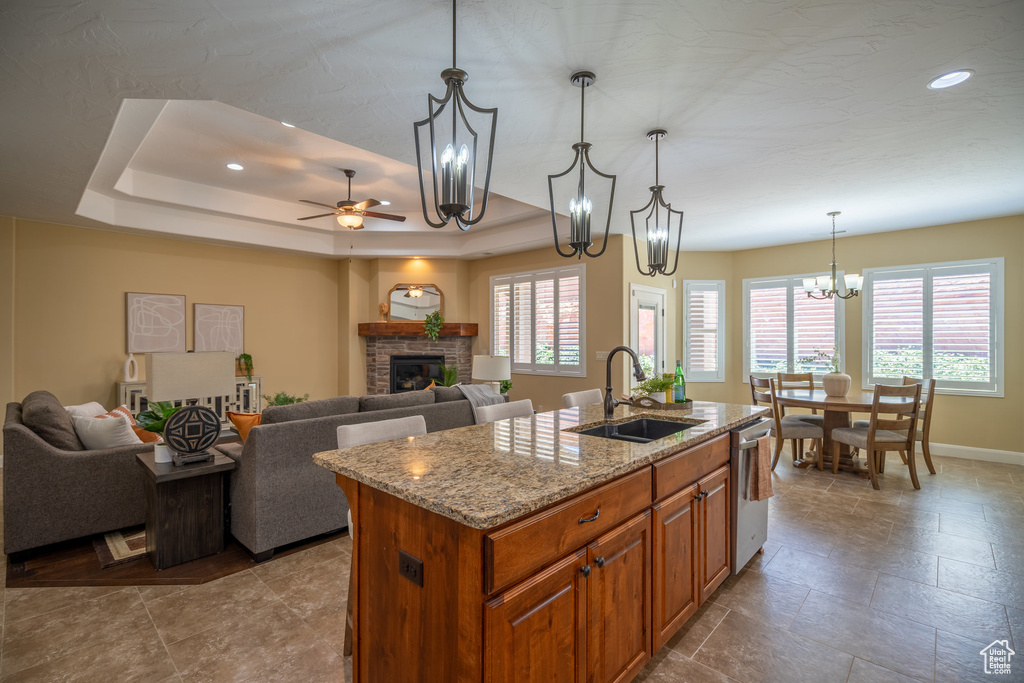 Kitchen featuring plenty of natural light, an island with sink, a tray ceiling, and a fireplace