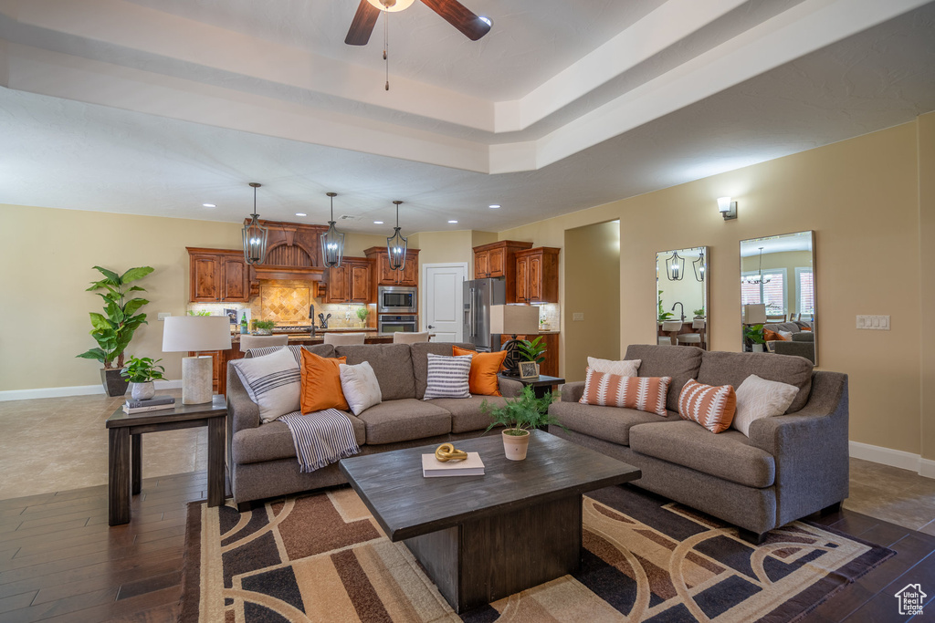 Living room with a tray ceiling, dark hardwood / wood-style floors, and ceiling fan