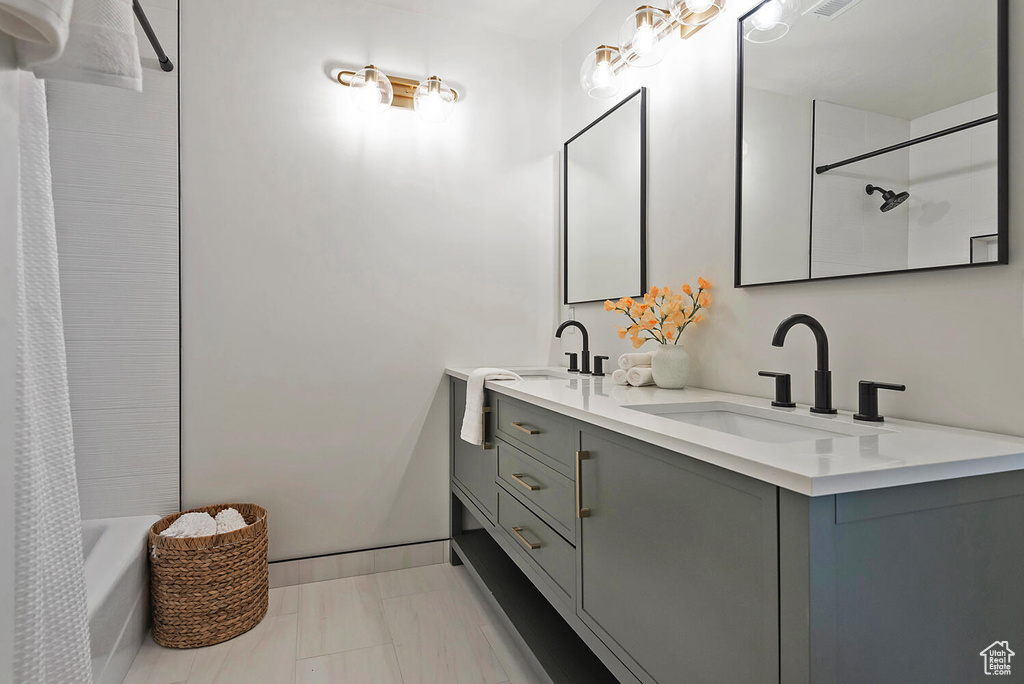 Bathroom featuring dual vanity, tile floors, and shower / tub combo