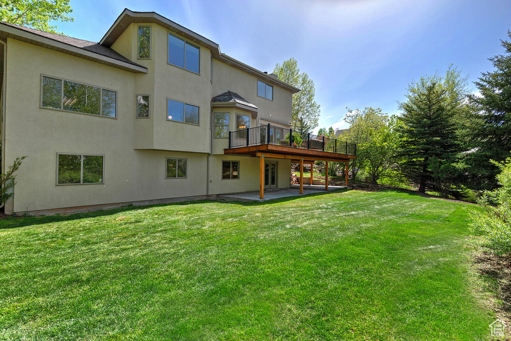 Back of house featuring a patio, a deck, and a lawn