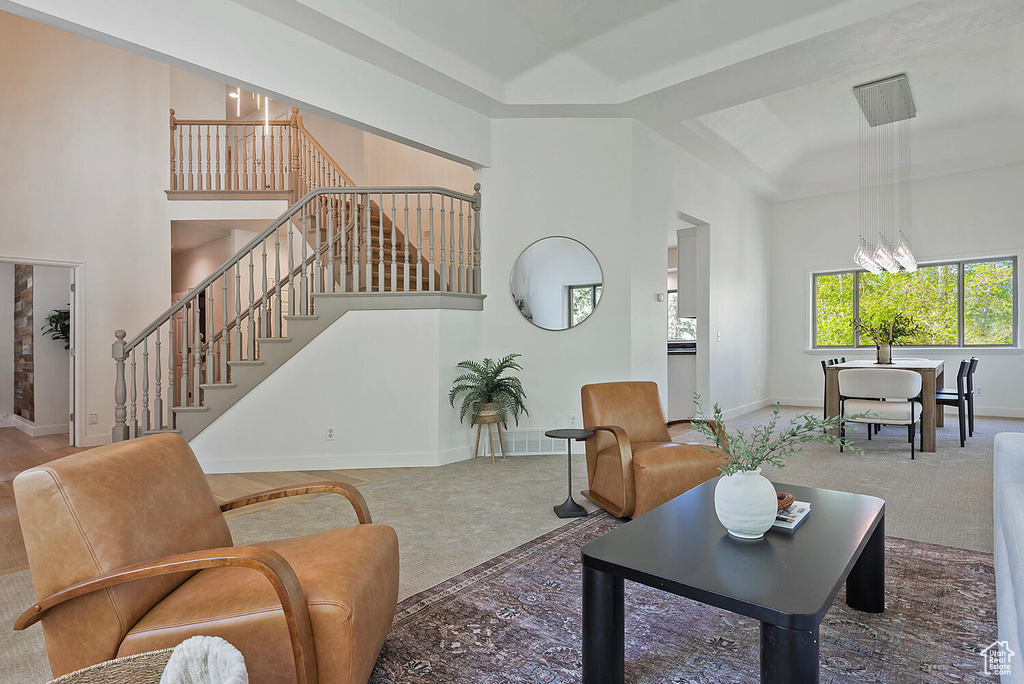 Carpeted living room featuring a chandelier and a towering ceiling