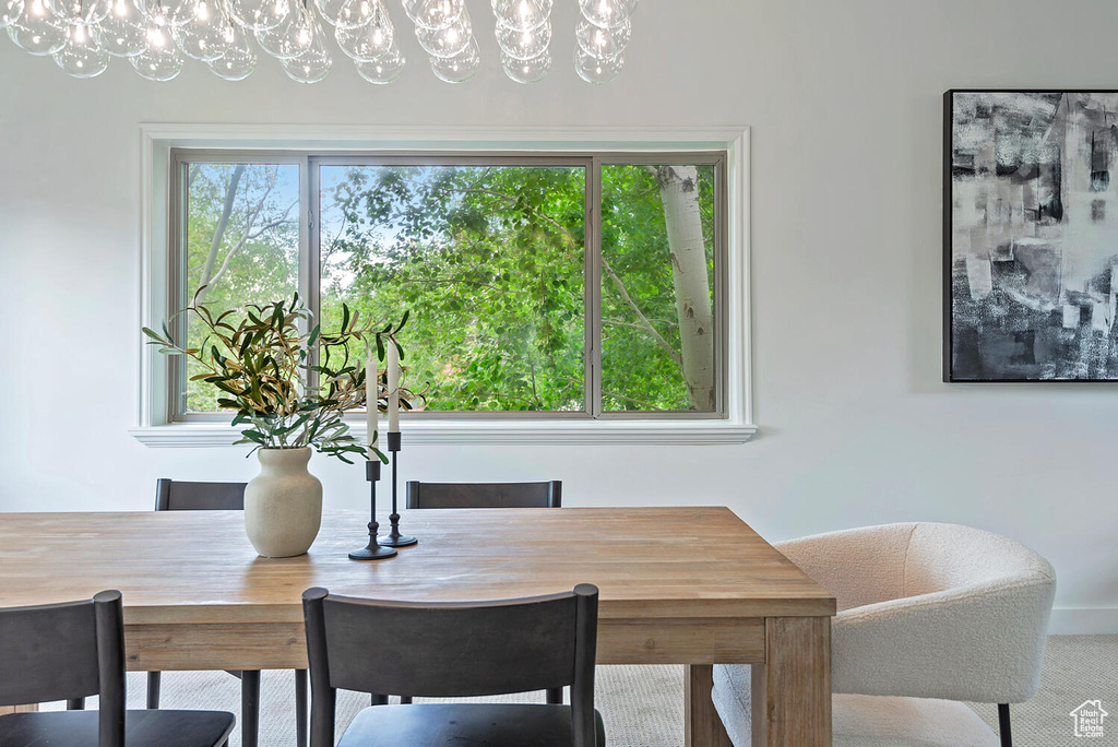 Carpeted dining room featuring a notable chandelier and a healthy amount of sunlight