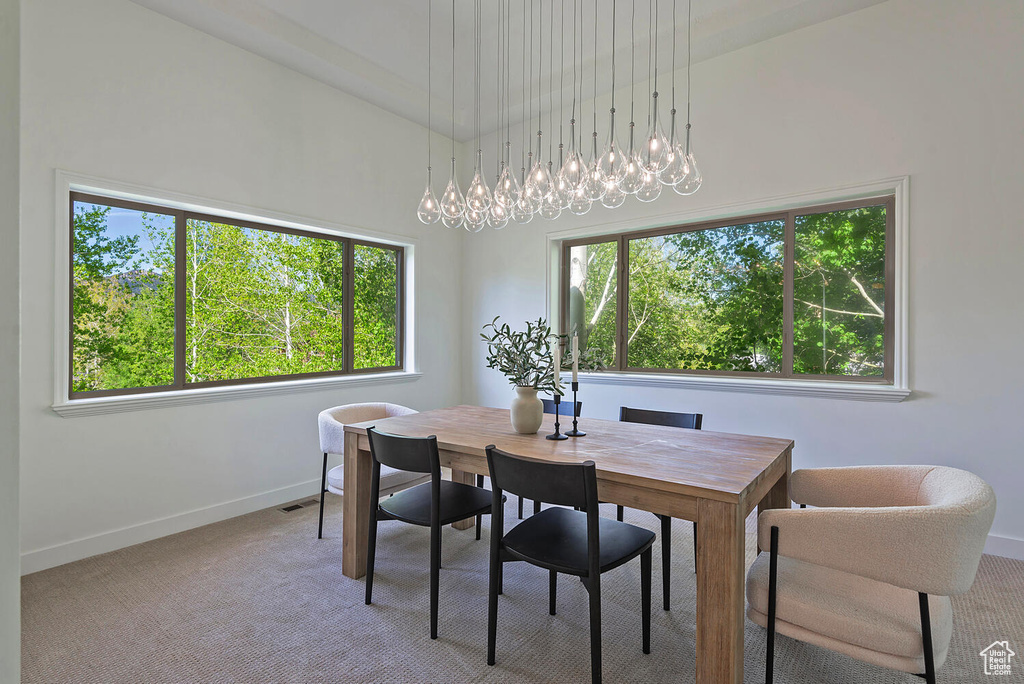 Carpeted dining room featuring an inviting chandelier and a towering ceiling