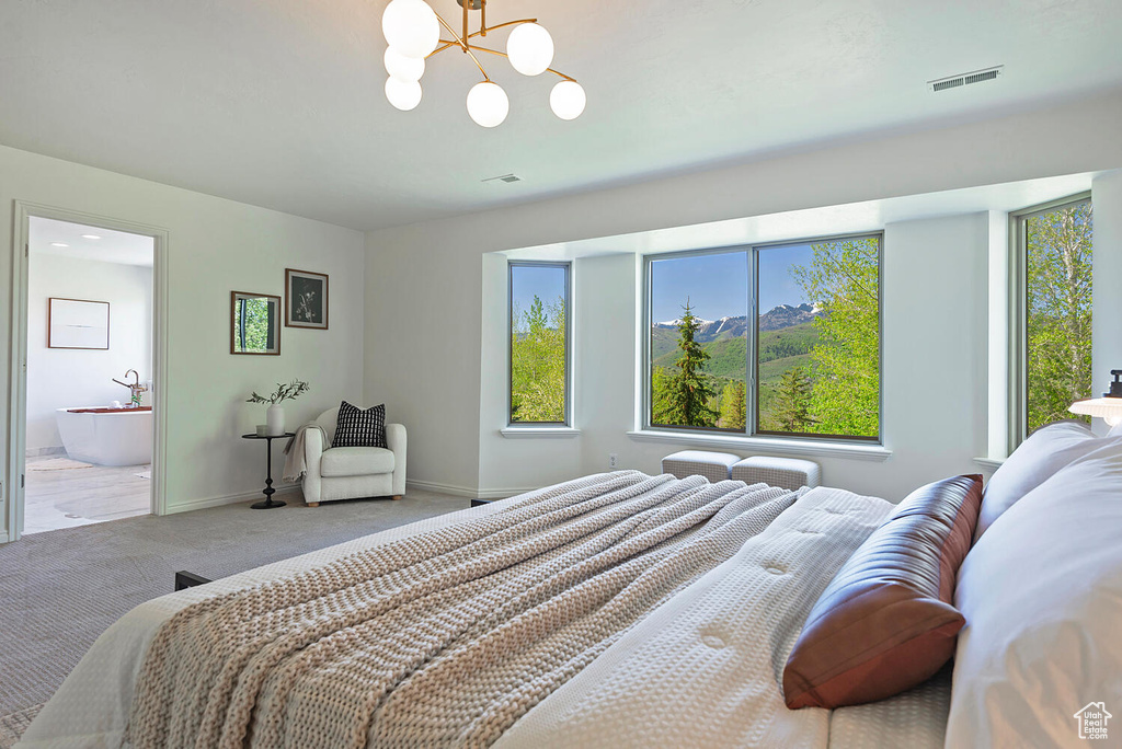 Carpeted bedroom featuring a chandelier and ensuite bathroom