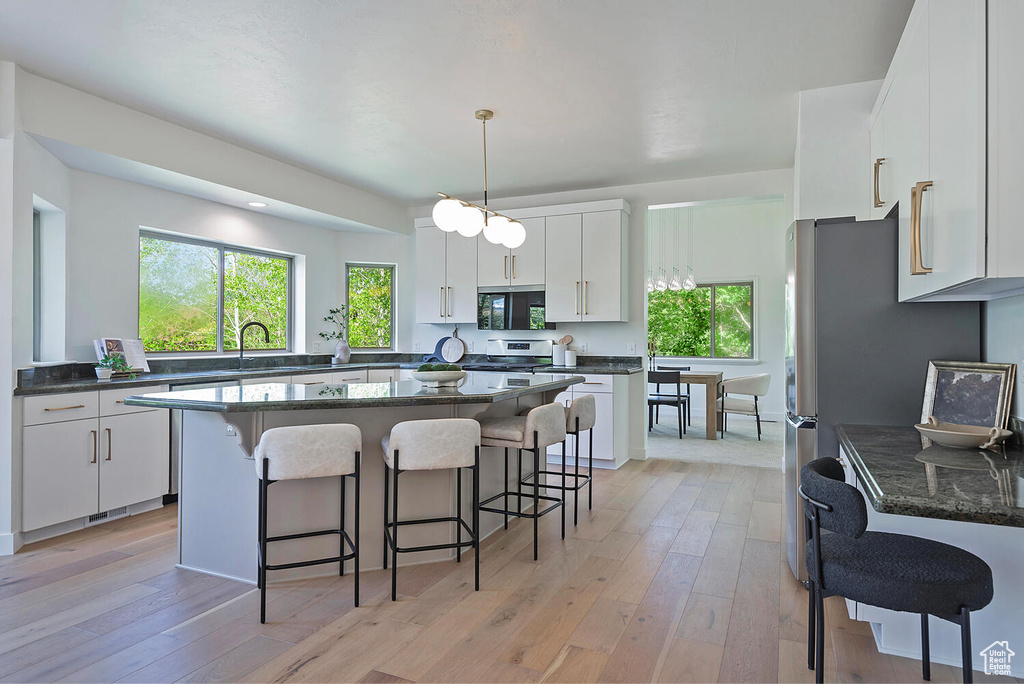 Kitchen with white cabinetry, a wealth of natural light, and light hardwood / wood-style flooring