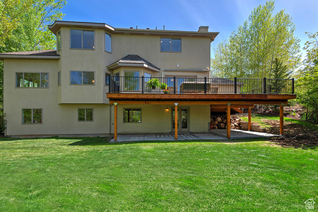 Rear view of property featuring a yard, a patio area, and a wooden deck