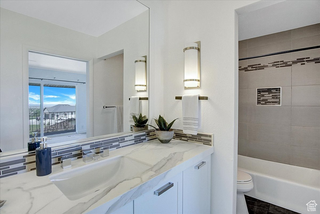 Full bathroom with tiled shower / bath combo, backsplash, vanity, and toilet