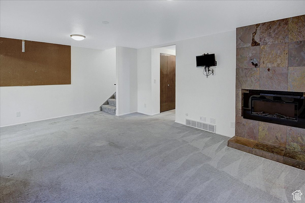 Unfurnished living room with a tiled fireplace and carpet