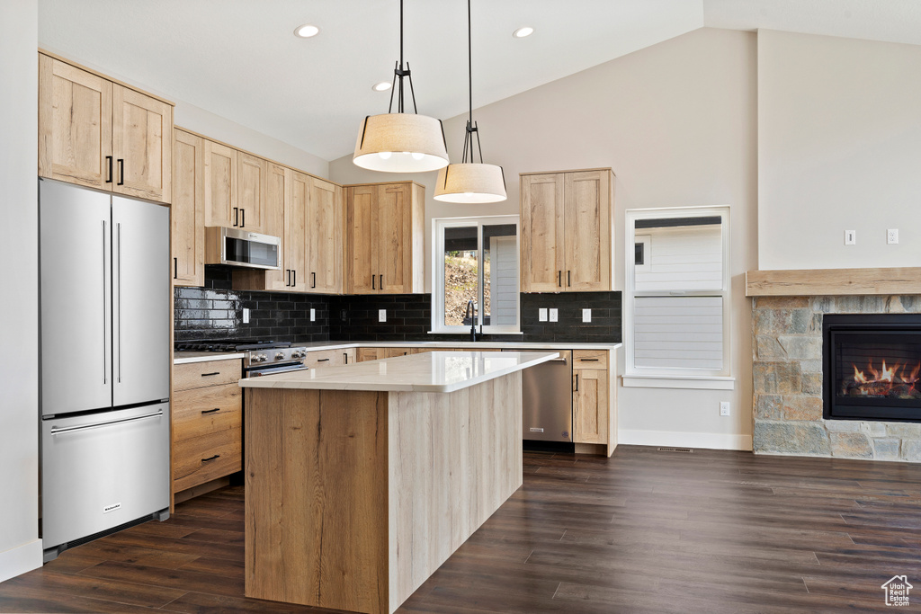 Kitchen with decorative light fixtures, appliances with stainless steel finishes, dark hardwood / wood-style flooring, and lofted ceiling