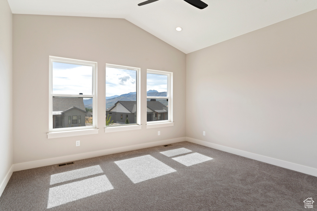 Carpeted spare room featuring lofted ceiling and ceiling fan