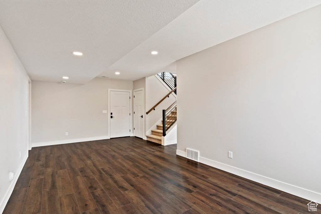 Basement with a textured ceiling and dark hardwood / wood-style floors