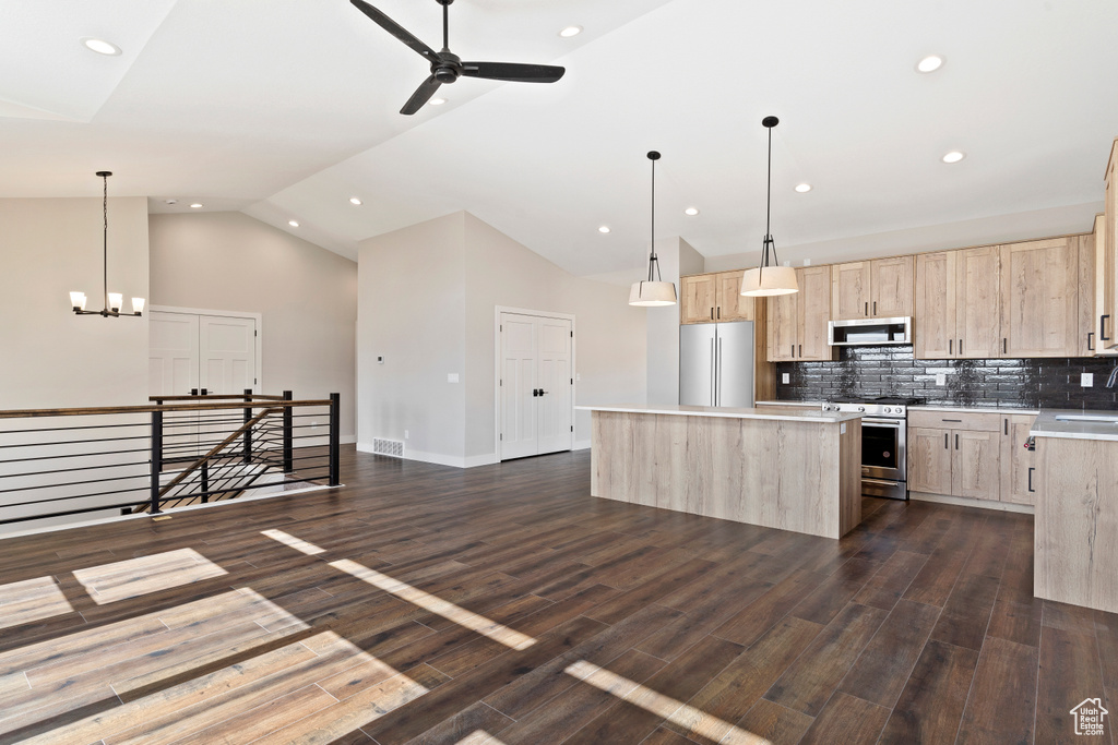 Kitchen featuring light brown cabinetry, ceiling fan with notable chandelier, appliances with stainless steel finishes, and a kitchen island