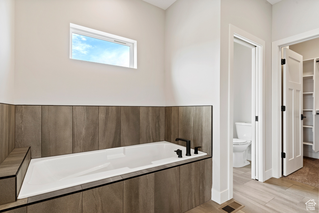 Bathroom with hardwood / wood-style flooring, a bathtub, and toilet