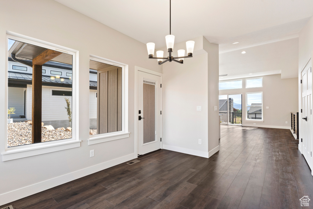 Unfurnished dining area featuring dark hardwood / wood-style floors and a notable chandelier