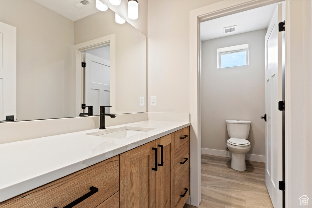 Bathroom featuring wood-type flooring, vanity, and toilet