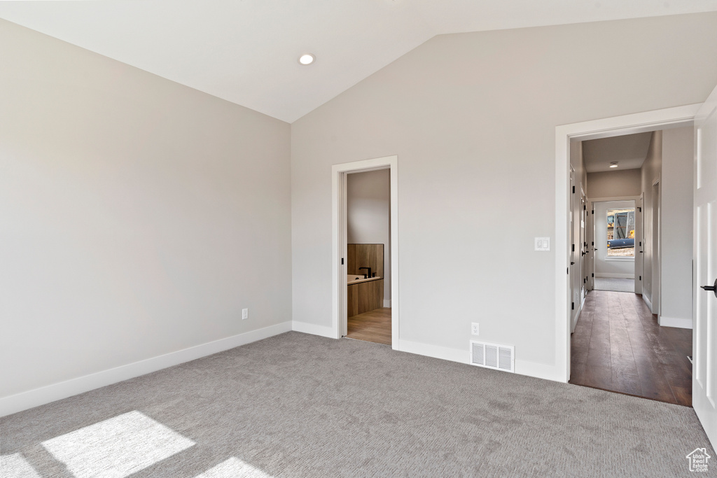 Unfurnished bedroom featuring carpet flooring, lofted ceiling, and ensuite bathroom