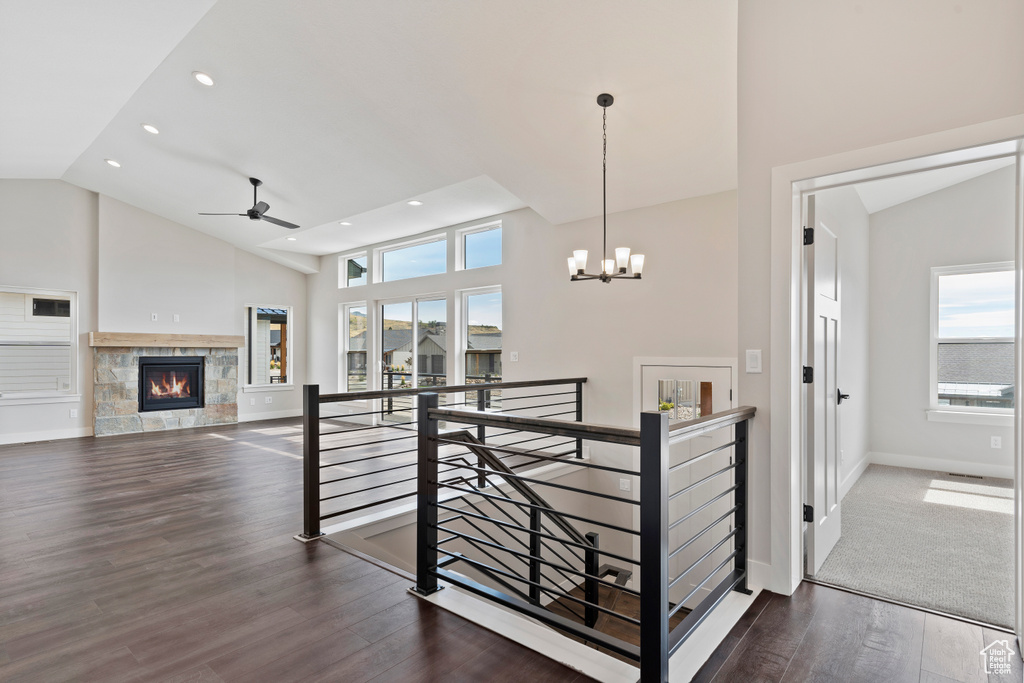 Corridor featuring high vaulted ceiling, dark hardwood / wood-style flooring, a chandelier, and a wealth of natural light