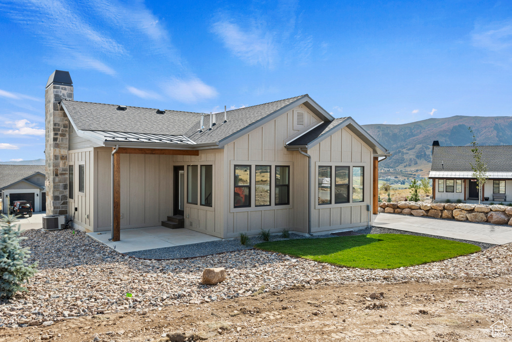 Rear view of house with a mountain view, a patio, and central air condition unit