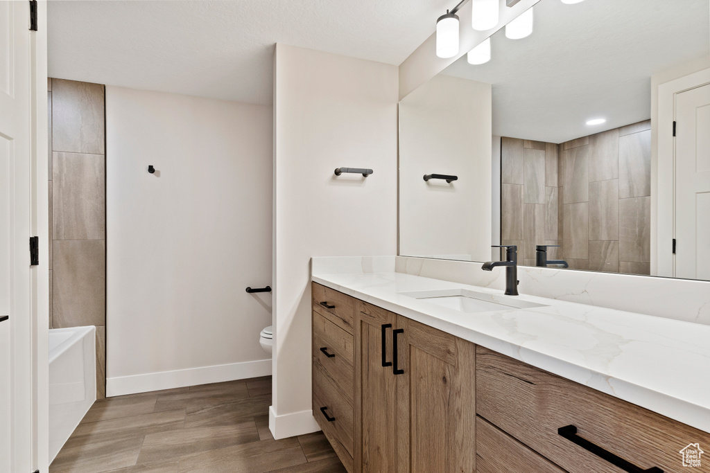 Full bathroom with wood-type flooring, vanity, toilet, and shower with separate bathtub