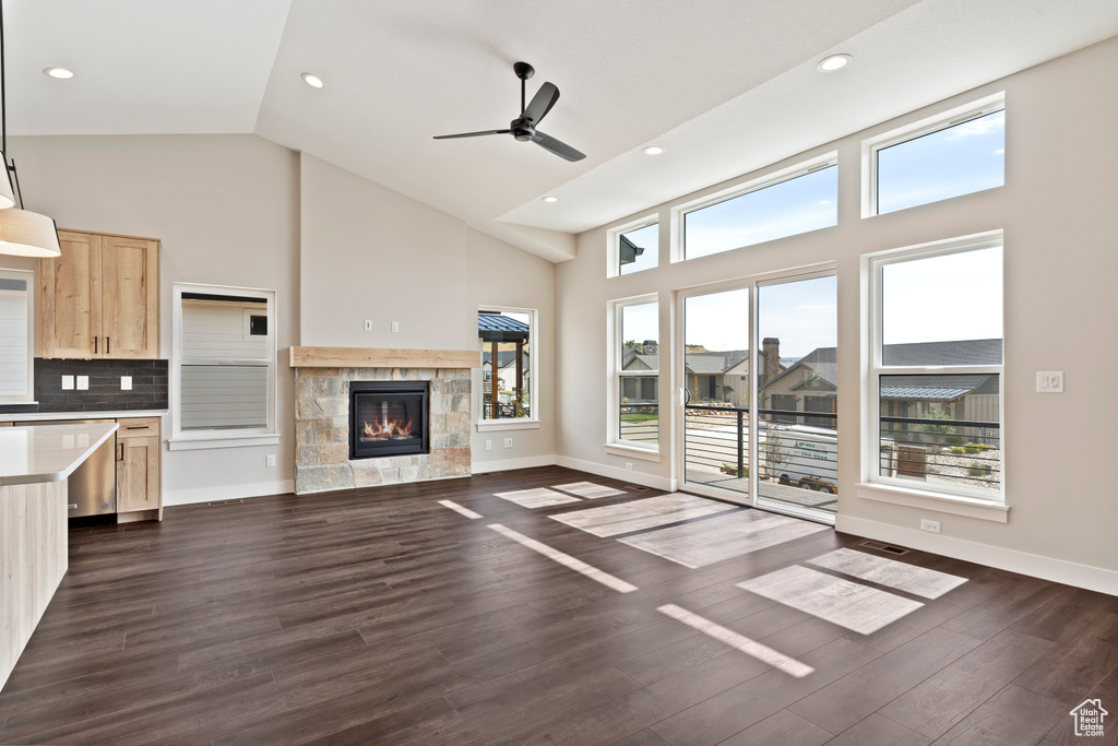 Unfurnished living room with high vaulted ceiling, a tiled fireplace, ceiling fan, and dark hardwood / wood-style floors