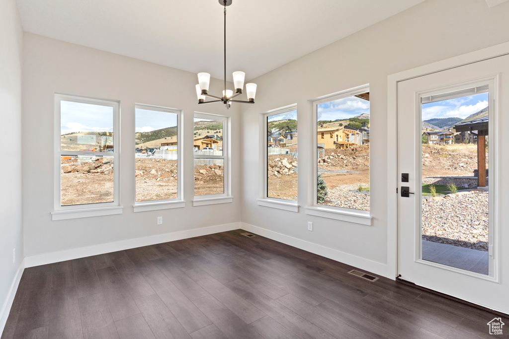 Unfurnished dining area with an inviting chandelier and dark hardwood / wood-style flooring