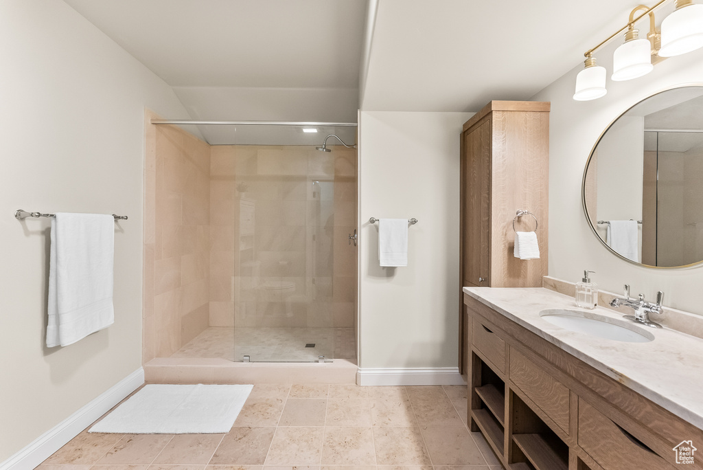 Bathroom featuring tile flooring, tiled shower, and vanity with extensive cabinet space