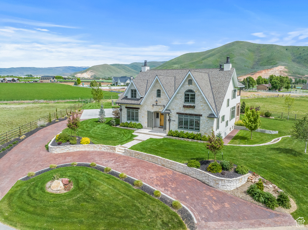 View of front of house with a front yard, a mountain view, and a rural view