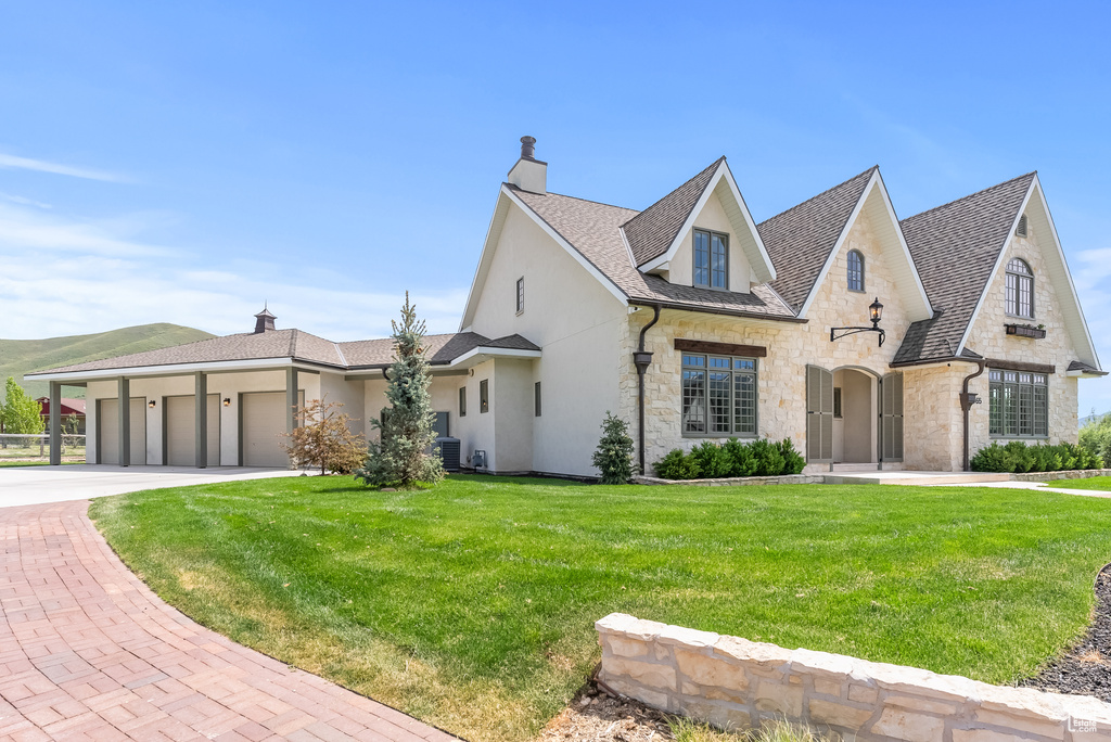 French country inspired facade with a garage and a front yard