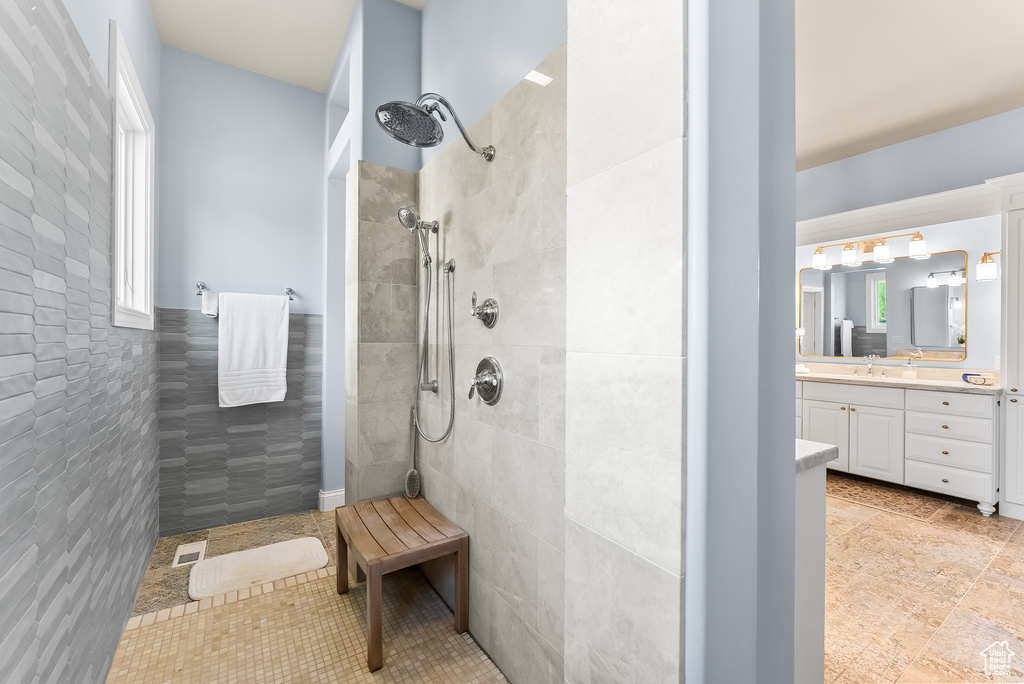 Bathroom featuring tile floors, tiled shower, and vanity