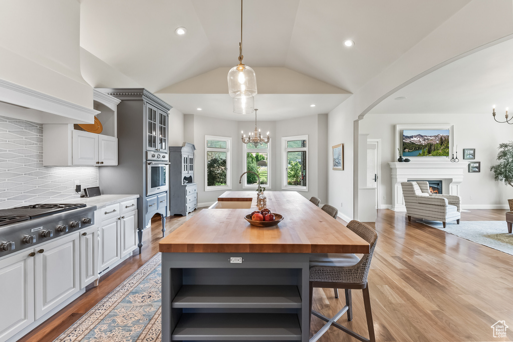 Kitchen featuring light hardwood / wood-style flooring, a kitchen island, stainless steel appliances, backsplash, and butcher block countertops