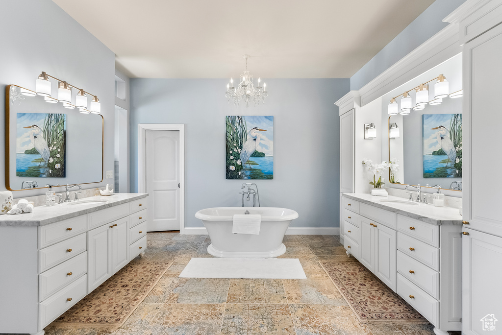 Bathroom with dual sinks, a bathing tub, an inviting chandelier, tile floors, and large vanity