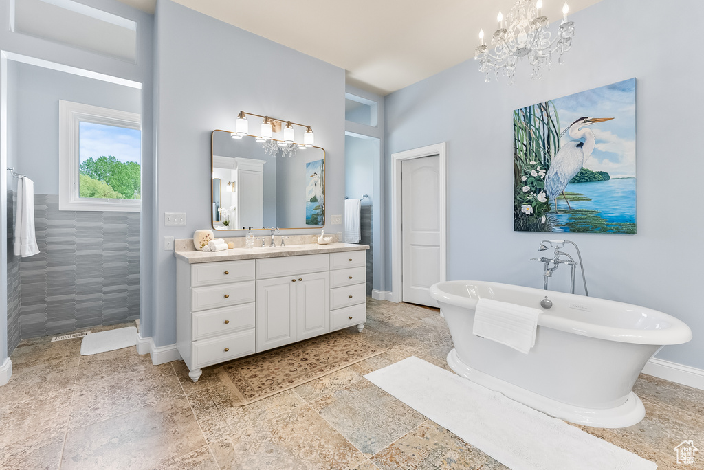 Bathroom featuring a notable chandelier, tile flooring, large vanity, and a tub