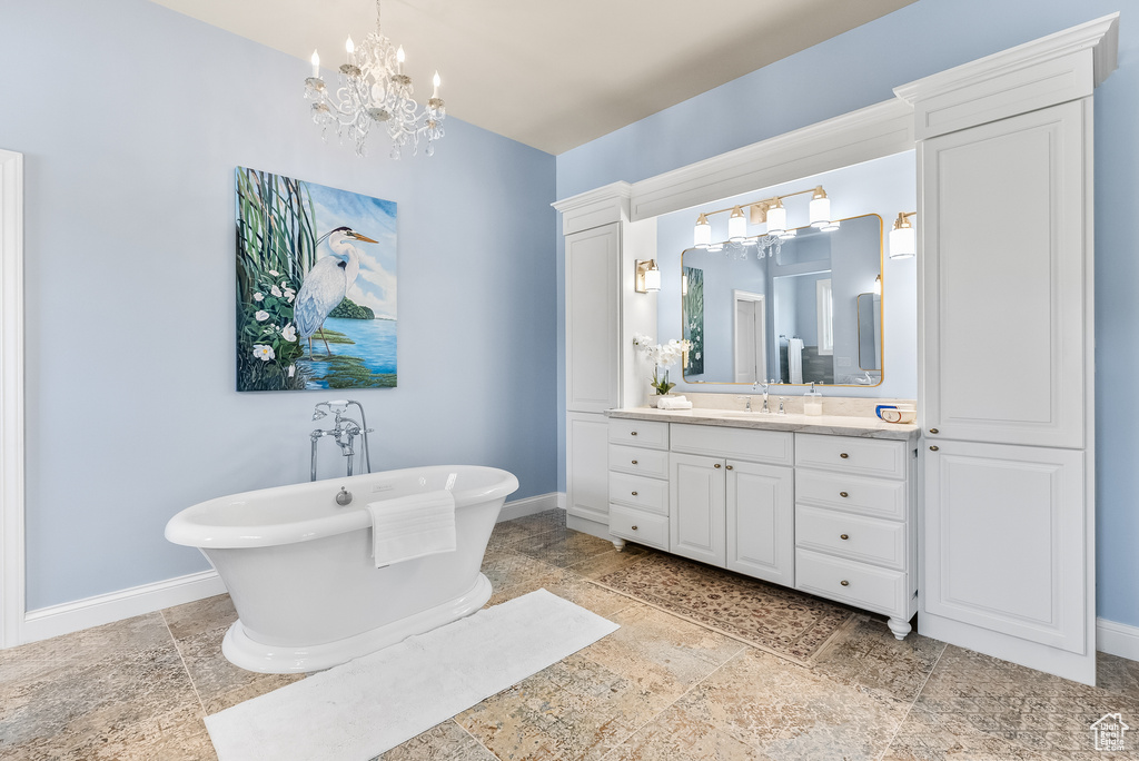 Bathroom featuring tile flooring, an inviting chandelier, a bath to relax in, and oversized vanity