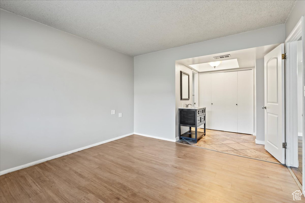 Unfurnished living room with light hardwood / wood-style flooring and a textured ceiling